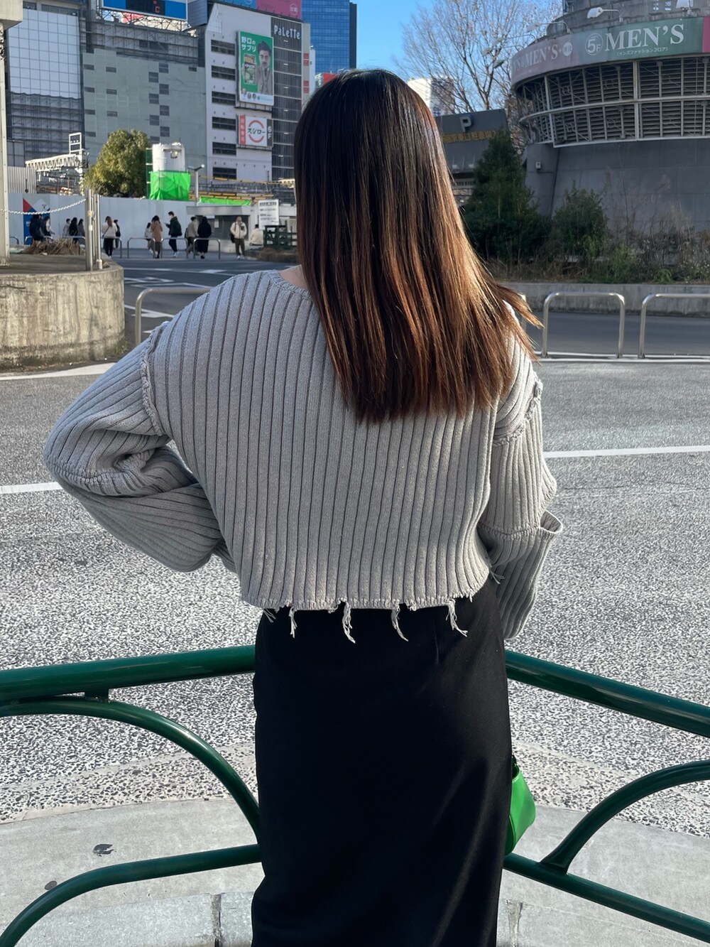 グレー系のニット/セーター、ブラック系のスカート、グリーン系のハンドバッグを着用したレディースの冬コーディネートの6枚目の写真