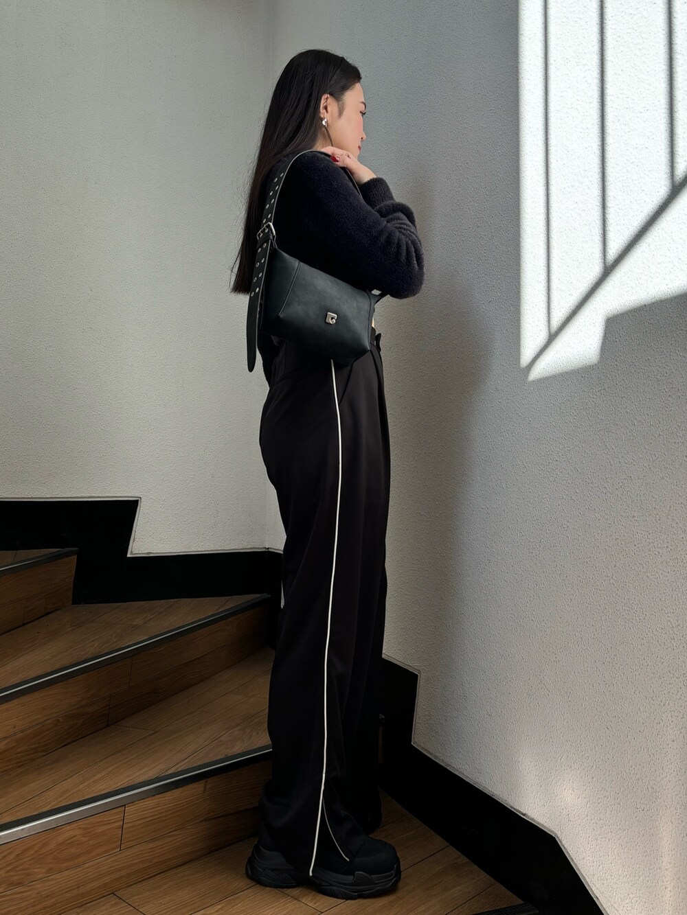 ブラック系のスラックス、ブラック系のニット/セーター、ブラック系のスニーカーを着用したレディースの冬コーディネートの2枚目の写真