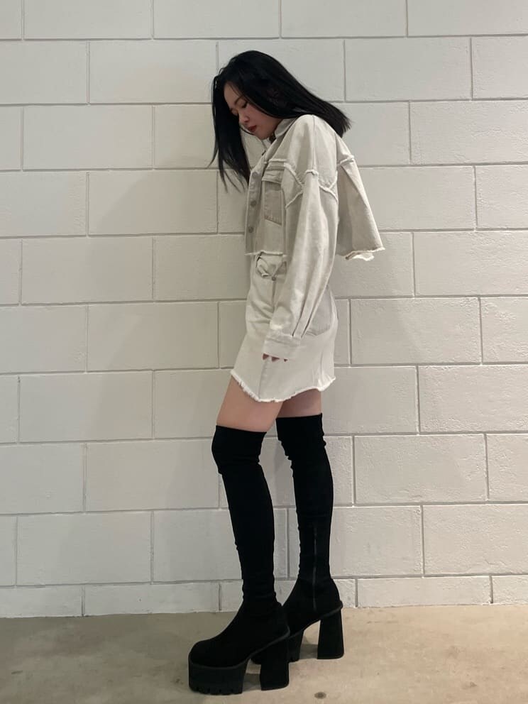 ホワイト系のデニムジャケット、ホワイト系のタンクトップ、ブラック系のブーツを着用したレディースの夏コーディネートの2枚目の写真