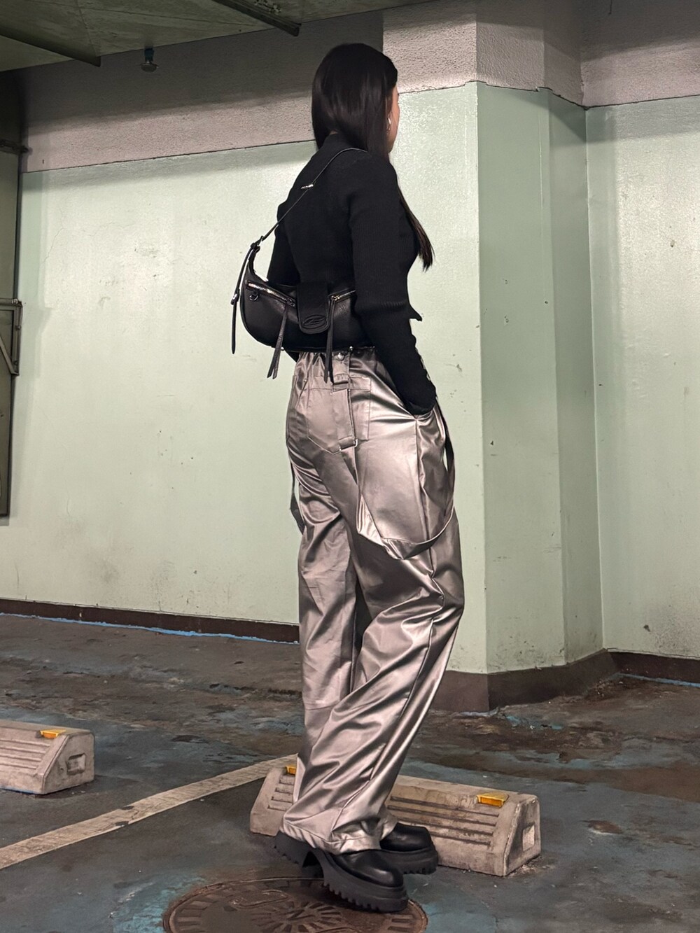 シルバー系のその他パンツ、ブラック系のニット/セーター、ブラック系のスニーカーを着用したレディースの冬コーディネートの2枚目の写真