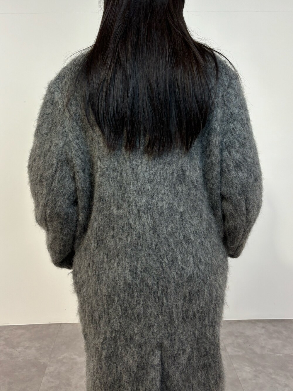 ブラック系のデニムパンツ、ブラック系のスニーカー、グレー系のチェスターコートを着用したレディースの冬コーディネートの4枚目の写真