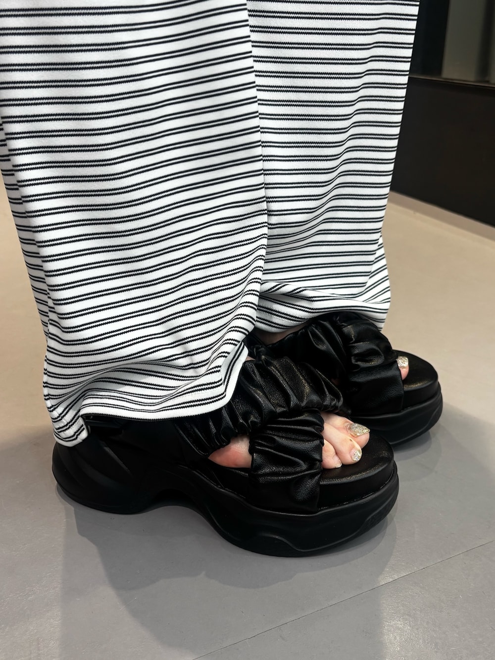 ブラック系のサンダル、ホワイト系のその他パンツ、ホワイト系のTシャツ/カットソーを着用したレディースの夏コーディネートの6枚目の写真