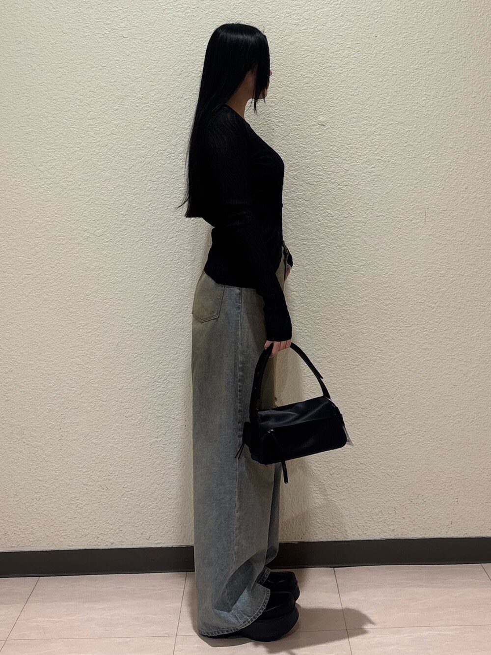 ブラック系のブーツ、ブラック系のハンドバッグ、ブルー系のデニムパンツを着用したレディースの春コーディネートの2枚目の写真