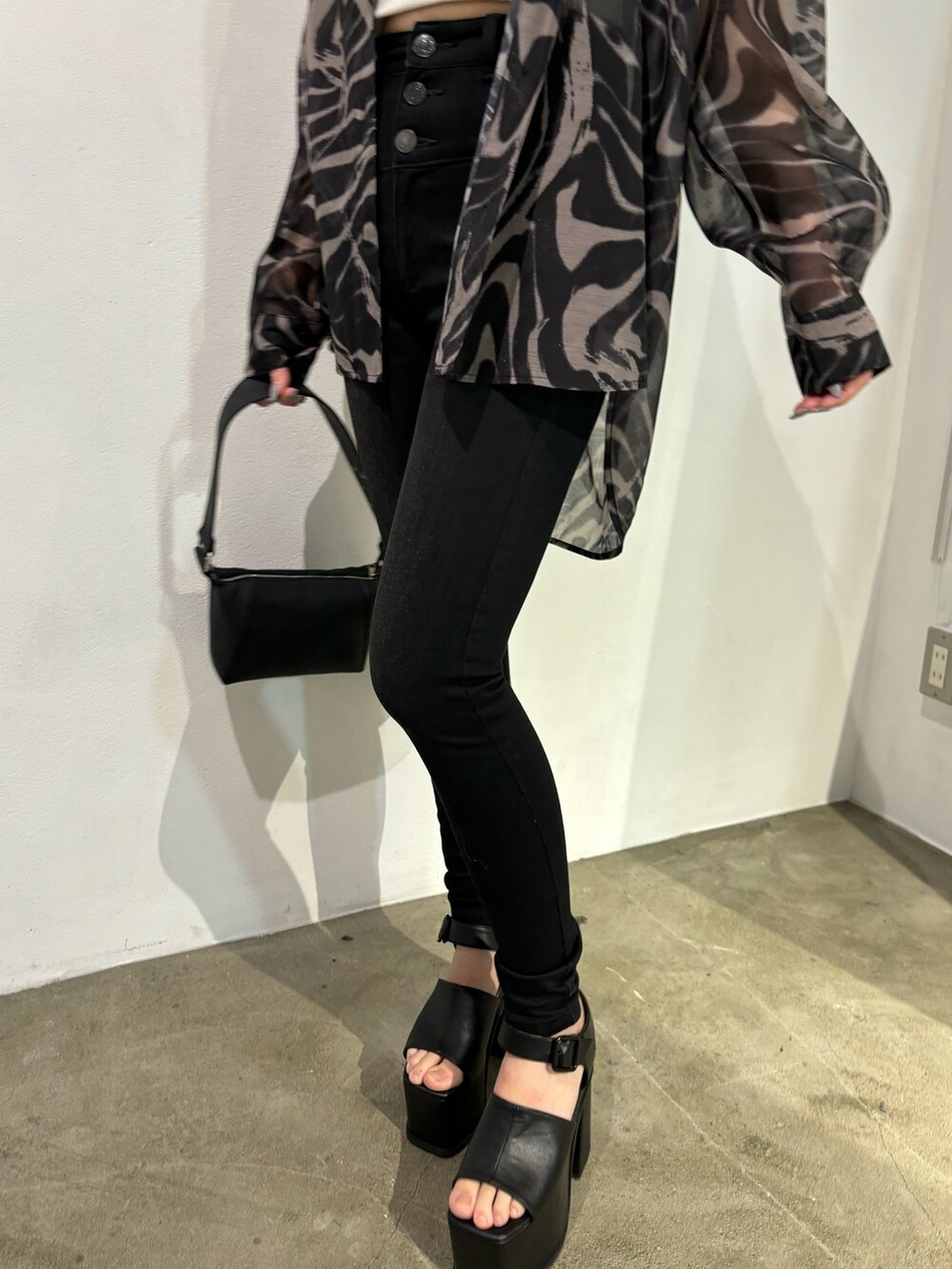 ブラック系のデニムパンツ、ベージュ系のシャツ/ブラウス、ブラック系のショルダーバッグを着用したレディースの春コーディネートの8枚目の写真