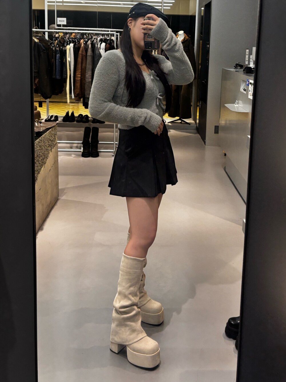 ホワイト系のブーツ、ブラック系のスカート、グレー系のニット/セーターを着用したレディースの秋コーディネートの2枚目の写真