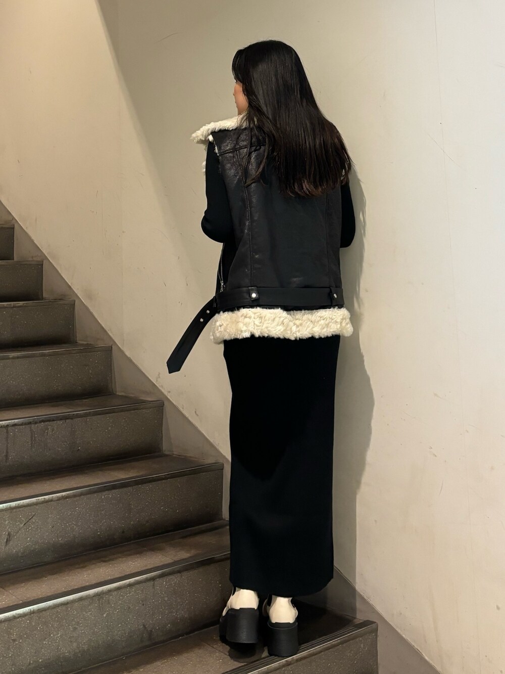 ブラック系のムートンコート、ブラック系のワンピース、ホワイト系のブーツを着用したレディースの秋コーディネートの3枚目の写真