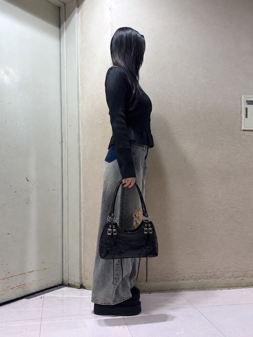 ブラック系のスリッポン、ブルー系のデニムパンツ、ブラック系のニット/セーターを着用したレディースの秋コーディネートの3枚目の写真