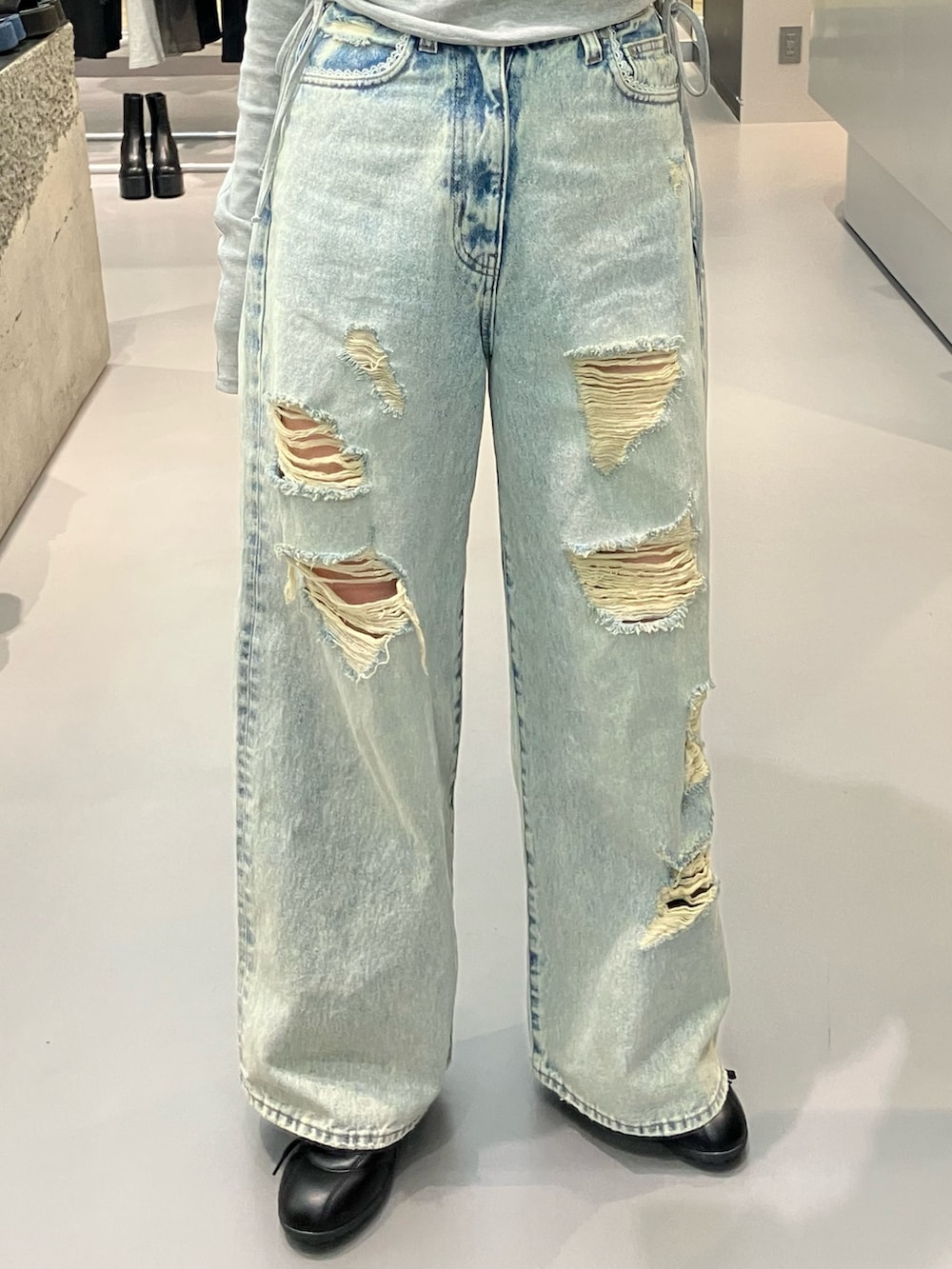 ブルー系のデニムパンツ、グレー系のTシャツ/カットソー、ブラック系のスニーカーを着用したレディースの春コーディネートの4枚目の写真