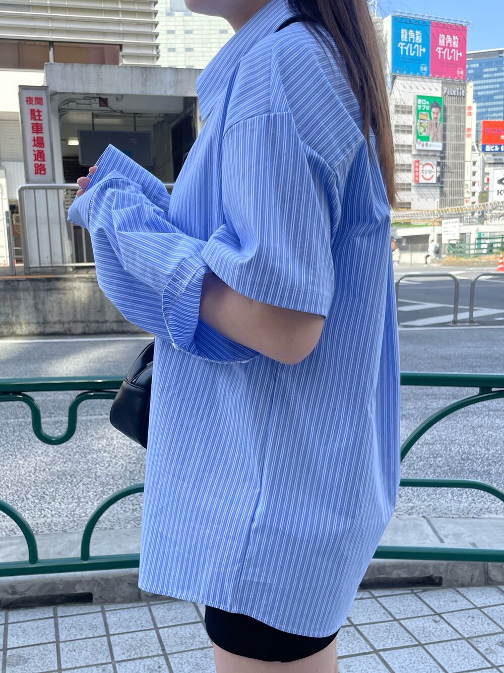 ブラック系のスカート、ブラック系のブーツ、ブラック系のハンドバッグを着用したレディースの春コーディネートの7枚目の写真