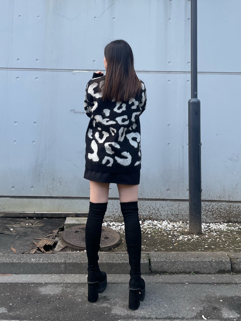 ブラック系のニット/セーター、ブラック系のスカート、ブラック系のブーツを着用したレディースの冬コーディネートの2枚目の写真