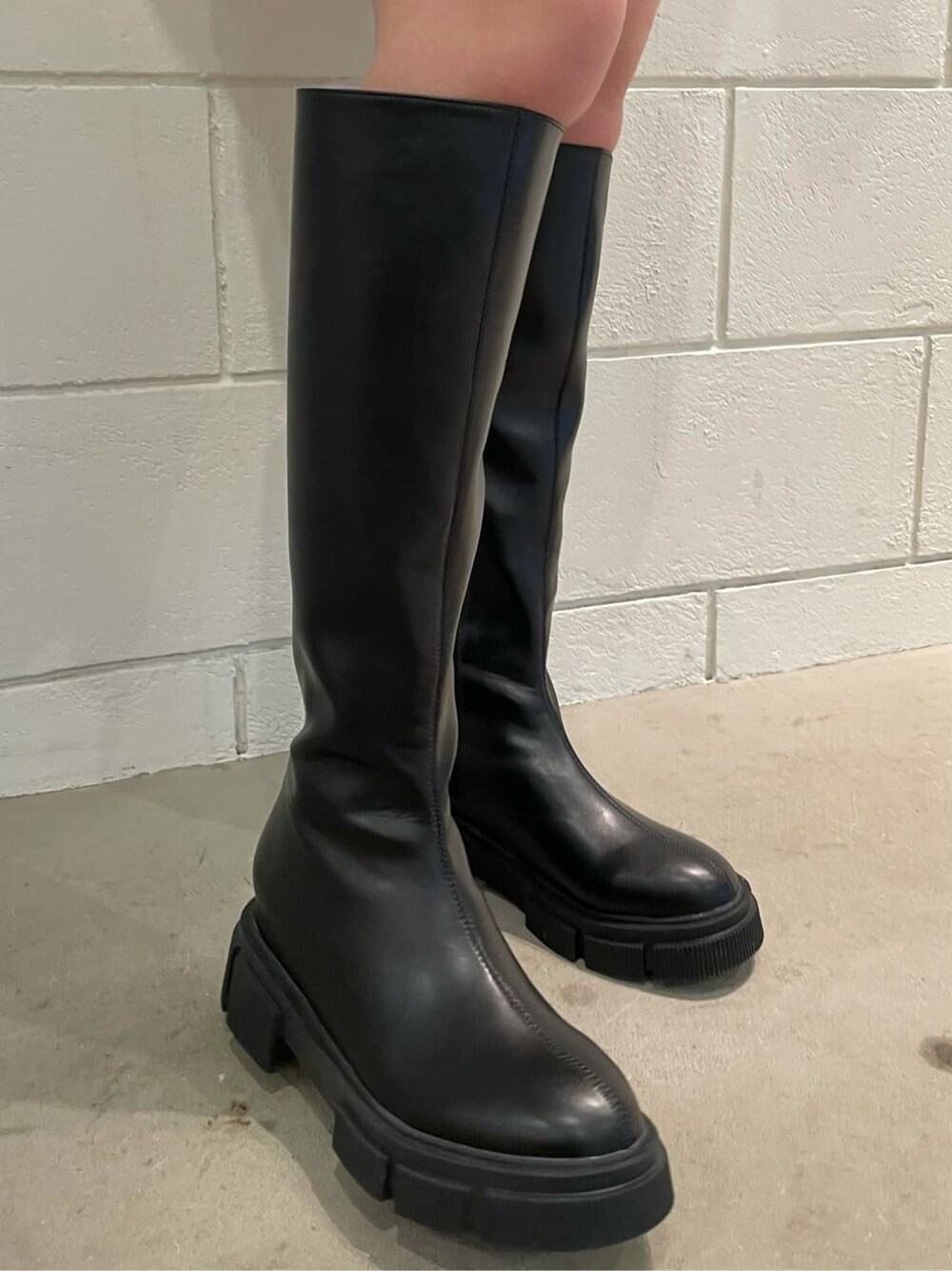 ブラック系のブーツ、ブラック系のスカート、ブラック系のニット/セーターを着用したレディースの冬コーディネートの8枚目の写真