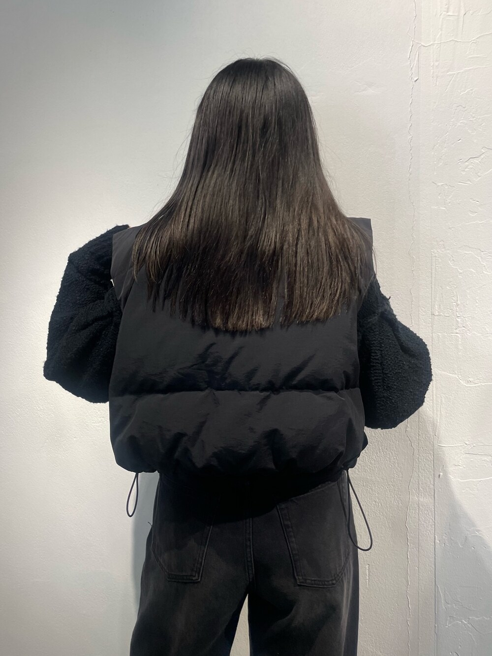 ブラック系のダウンベスト、ブラック系のカーディガン/ボレロ、ブラック系のデニムパンツを着用したレディースの夏コーディネートの6枚目の写真