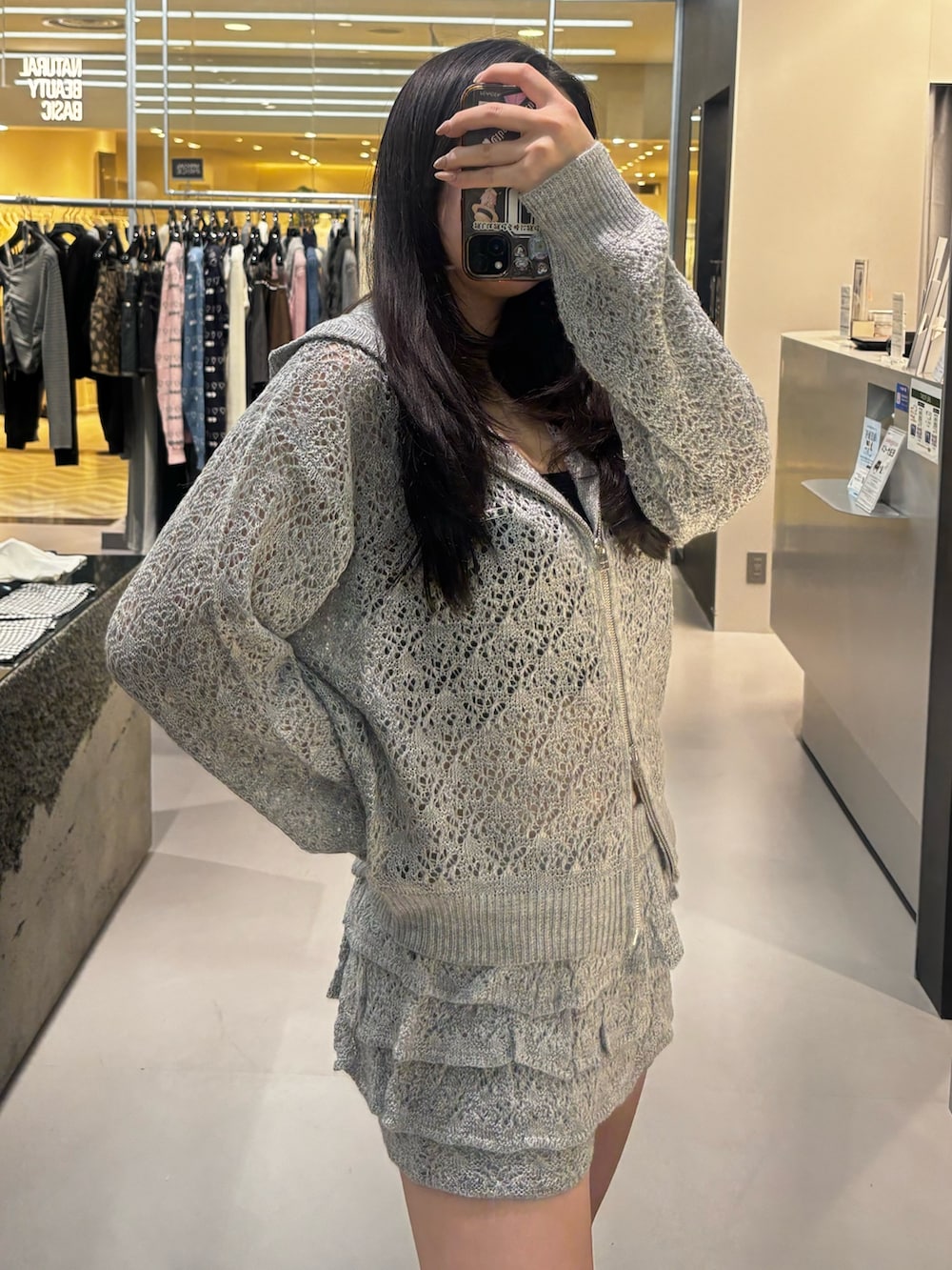 グレー系のパーカー、ブラック系のブーツ、グレー系のスカートを着用したレディースの冬コーディネートの4枚目の写真