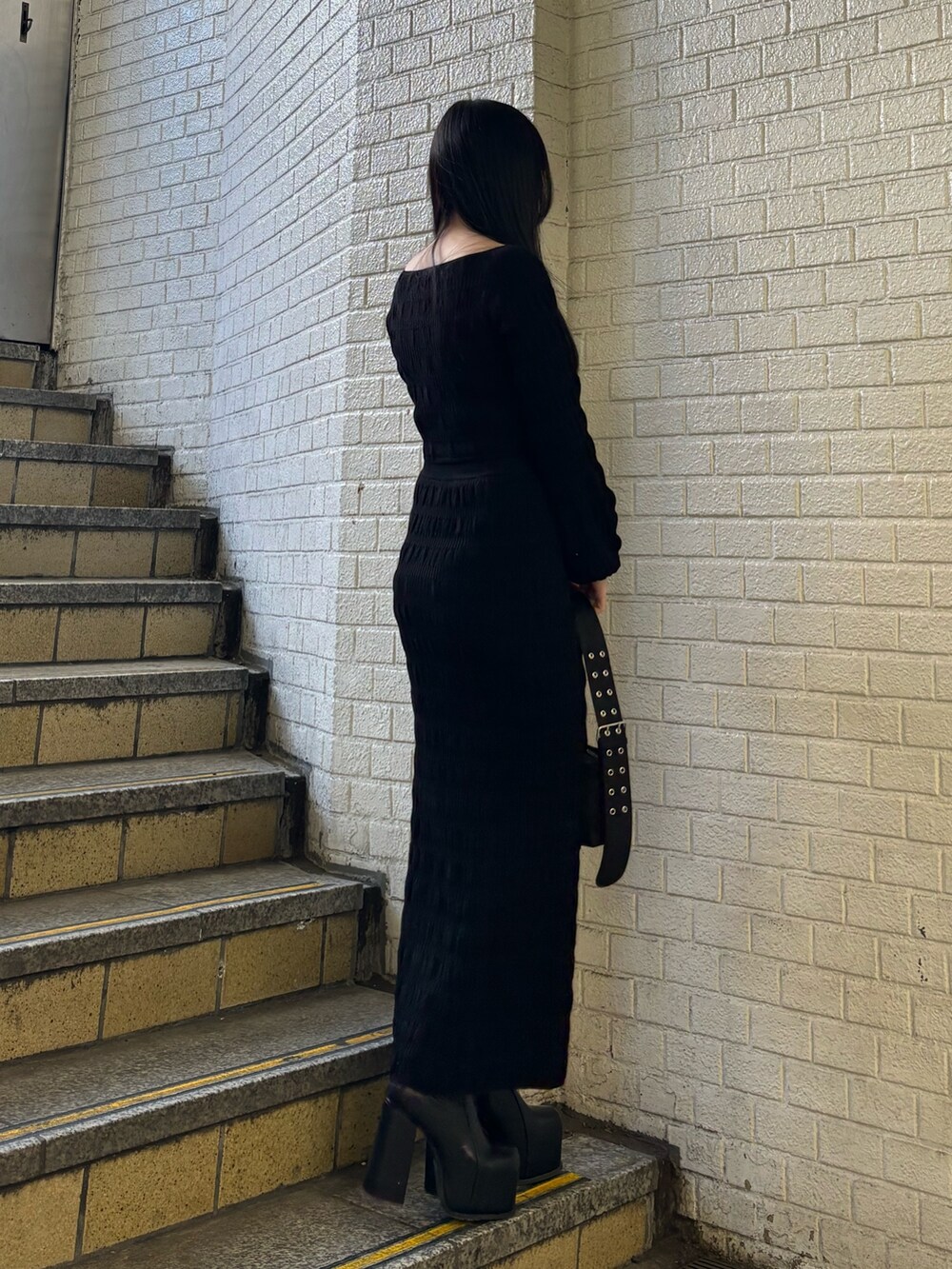 ブラック系のニット/セーター、ブラック系のスカート、ブラック系のショルダーバッグを着用したレディースの冬コーディネートの2枚目の写真