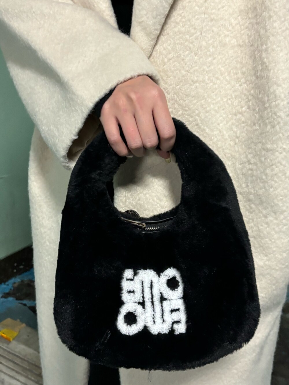 ブラック系のハンドバッグ、ブラック系のワンピース、ブラック系のブーツを着用したレディースの冬コーディネートの6枚目の写真