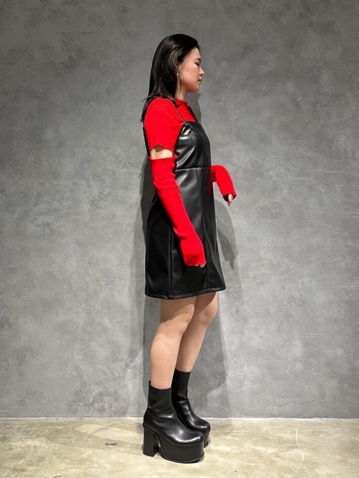 ブラック系のワンピース、レッド系のニット/セーター、ブラック系のブーツを着用したレディースの秋コーディネートの2枚目の写真