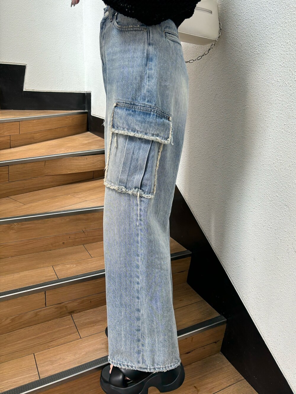 ブラック系のニット/セーター、ブルー系のデニムパンツを着用したレディースの春コーディネートの5枚目の写真