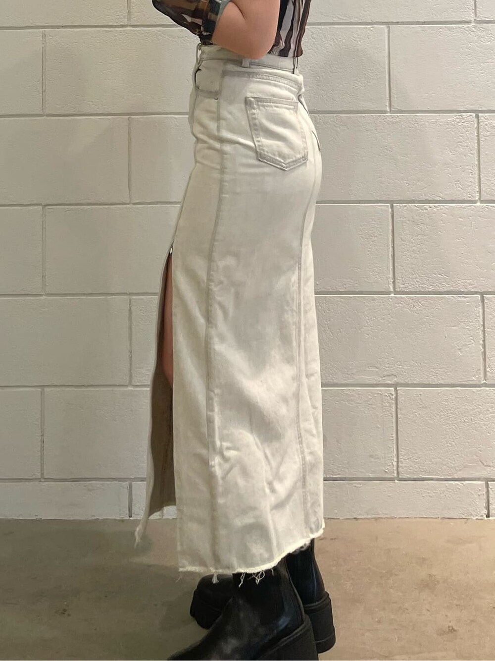 ホワイト系のスカート、ブラック系のブーツ、その他のTシャツ/カットソーを着用したレディースの夏コーディネートの6枚目の写真