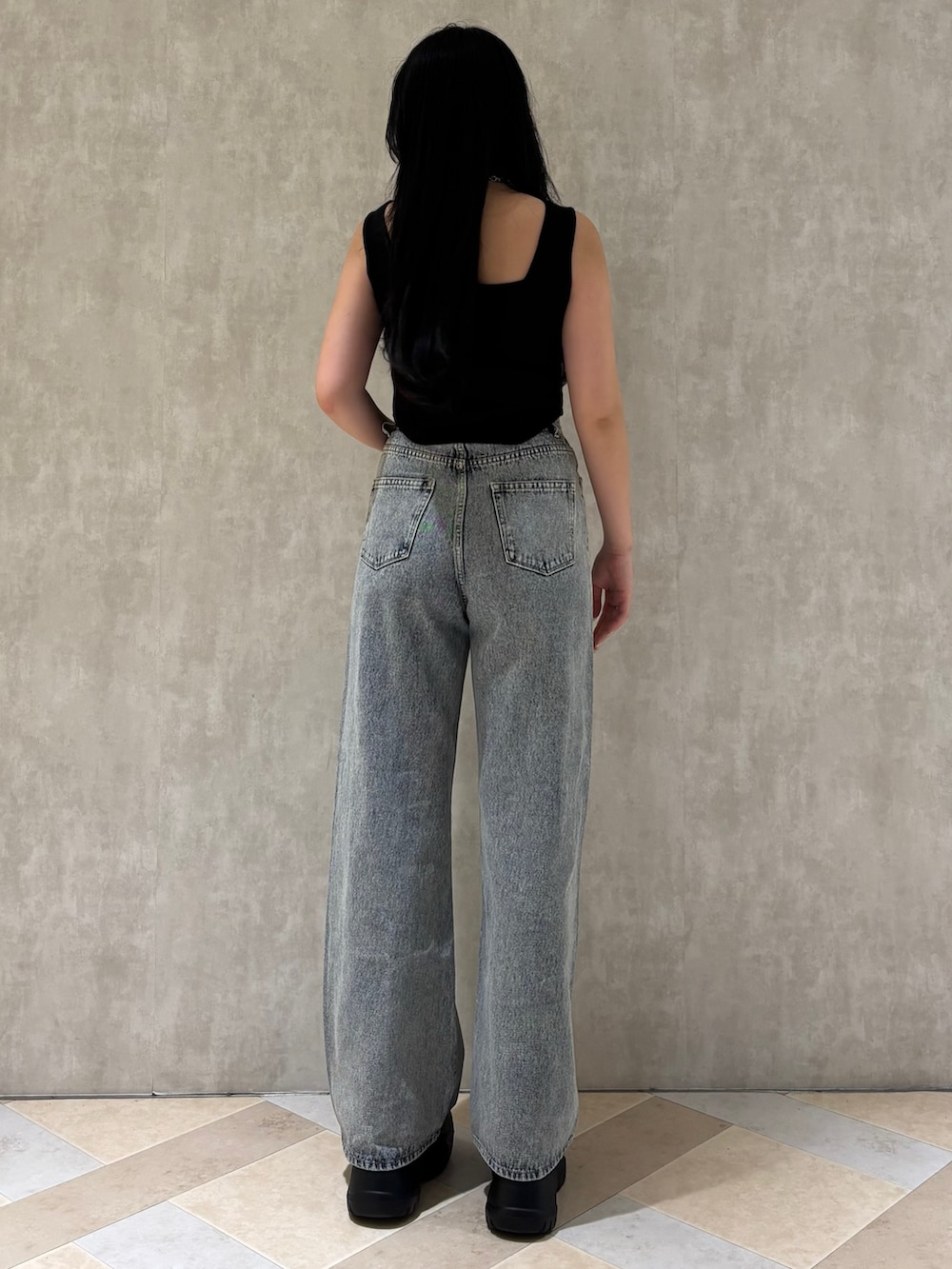 ブラック系のスニーカー、ブルー系のデニムパンツ、ブラック系のニット/セーターを着用したレディースの夏コーディネートの2枚目の写真