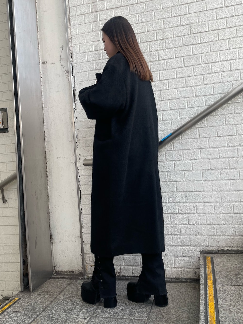 パープル系のチェスターコート、パープル系のニット/セーター、ブラック系のデニムパンツを着用したレディースの冬コーディネートの3枚目の写真