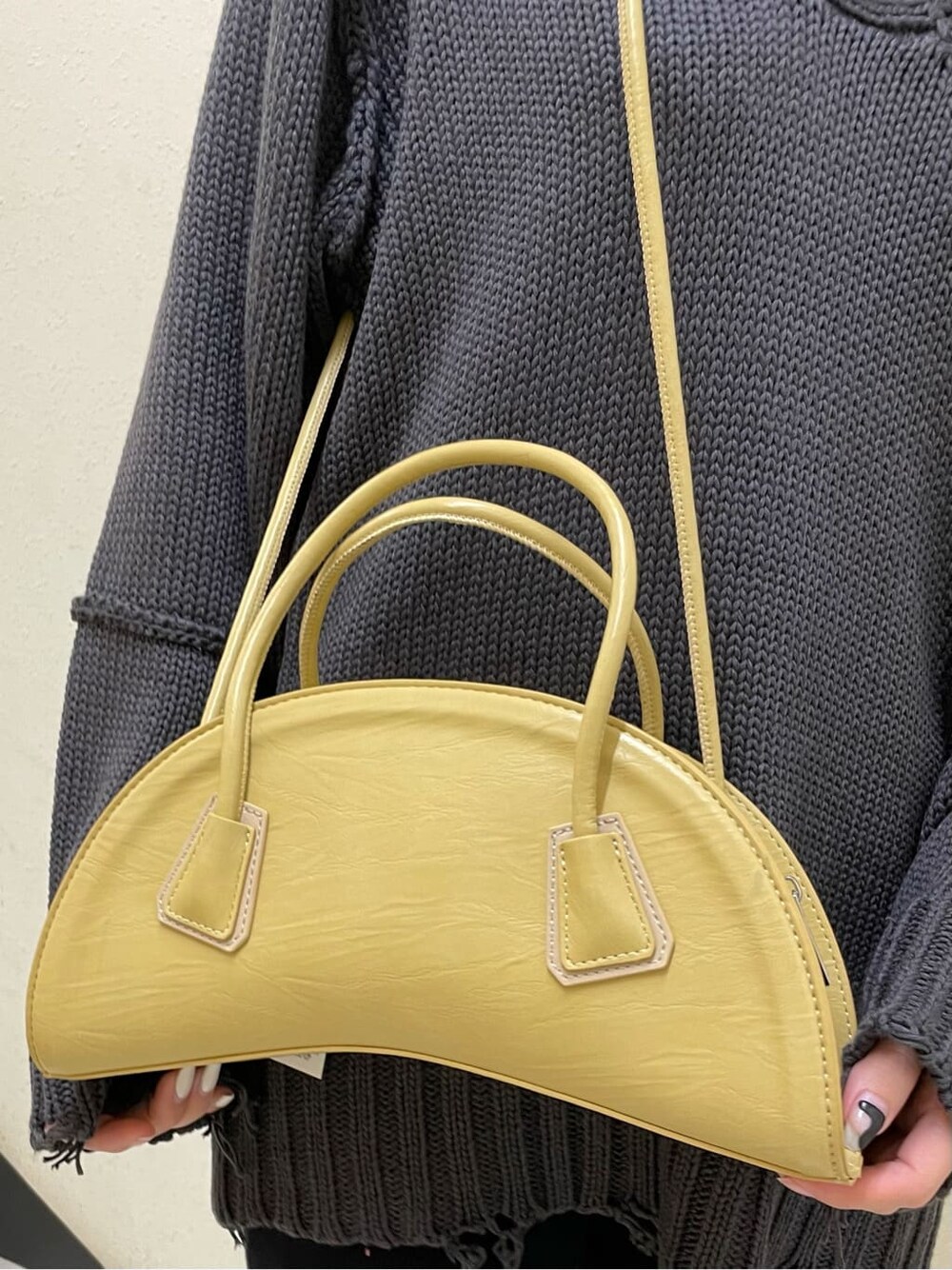 イエロー系のハンドバッグ、その他のブーツ、グレー系のニット/セーターを着用したレディースの秋コーディネートの6枚目の写真