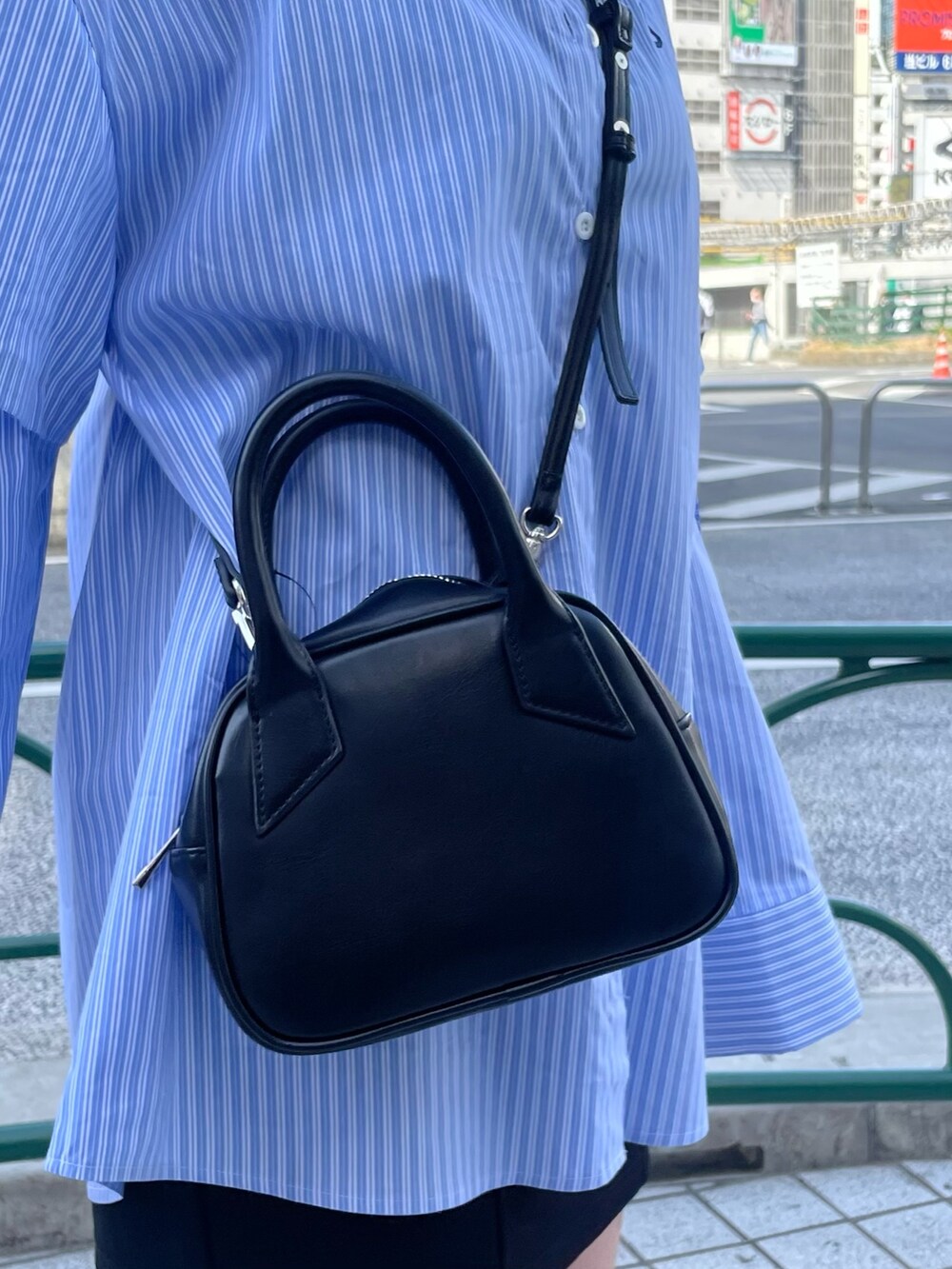 ブラック系のスカート、ブラック系のブーツ、ブラック系のハンドバッグを着用したレディースの春コーディネートの6枚目の写真