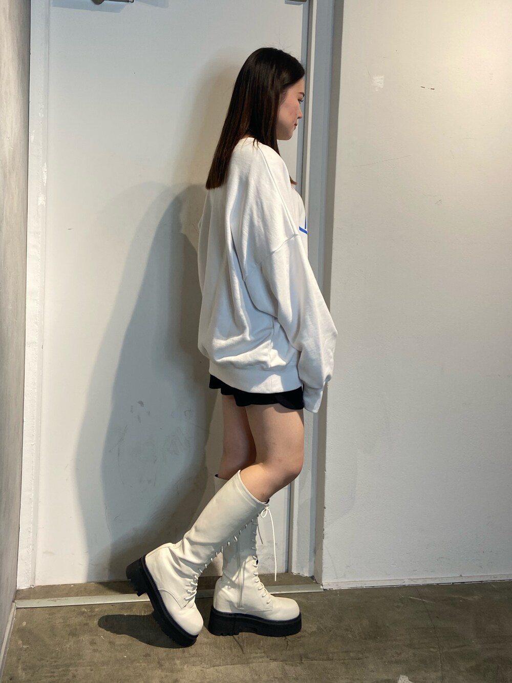 ホワイト系のスウェット、ホワイト系のブーツ、ブラック系のスカートを着用したレディースの冬コーディネートの2枚目の写真