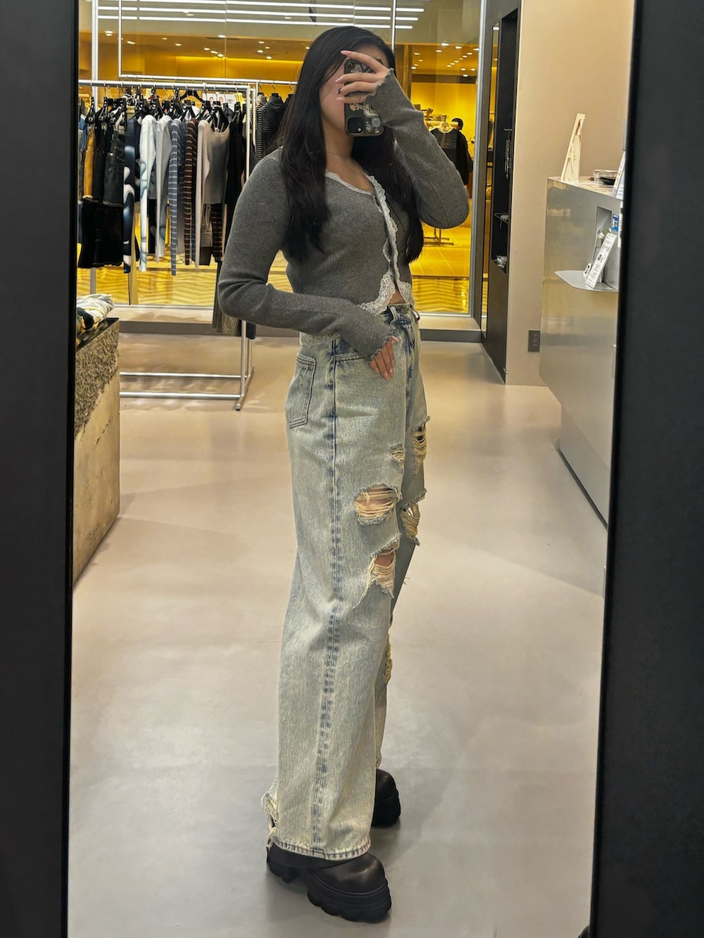 ブラック系のブーツ、ブルー系のデニムパンツ、グレー系のニット/セーターを着用したレディースの春コーディネートの2枚目の写真