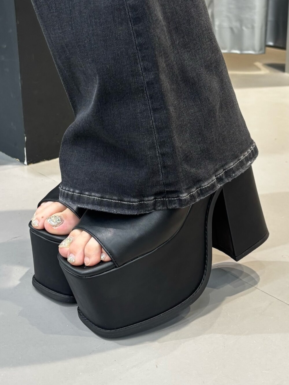 ホワイト系のハンドバッグ、ブラック系のサンダル、ブラック系のデニムパンツを着用したレディースの夏コーディネートの6枚目の写真