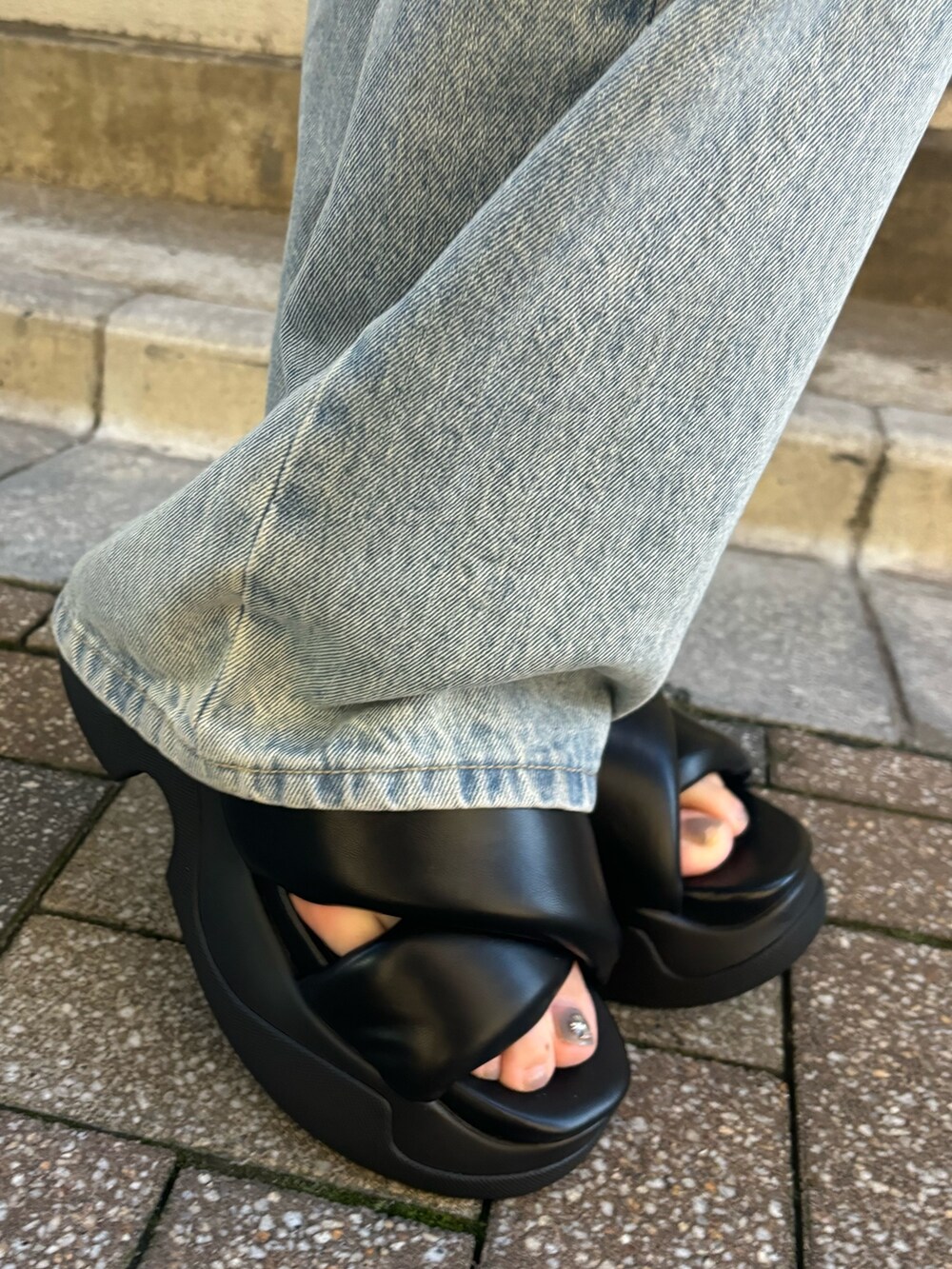 ホワイト系のデニムパンツ、ブラック系のニット/セーター、ブラック系のサンダルを着用したレディースの夏コーディネートの9枚目の写真