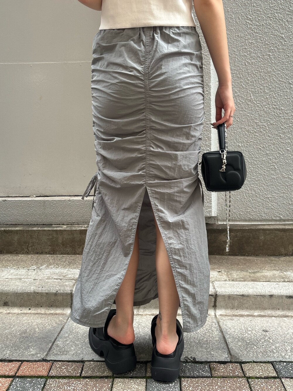 ブラック系のサンダル、ホワイト系のTシャツ/カットソー、ブラック系のハンドバッグを着用したレディースの夏コーディネートの8枚目の写真