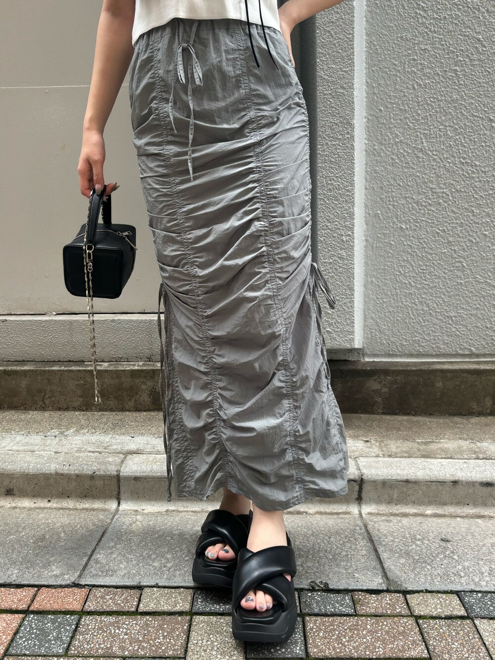 ブラック系のサンダル、ホワイト系のTシャツ/カットソー、ブラック系のハンドバッグを着用したレディースの夏コーディネートの6枚目の写真