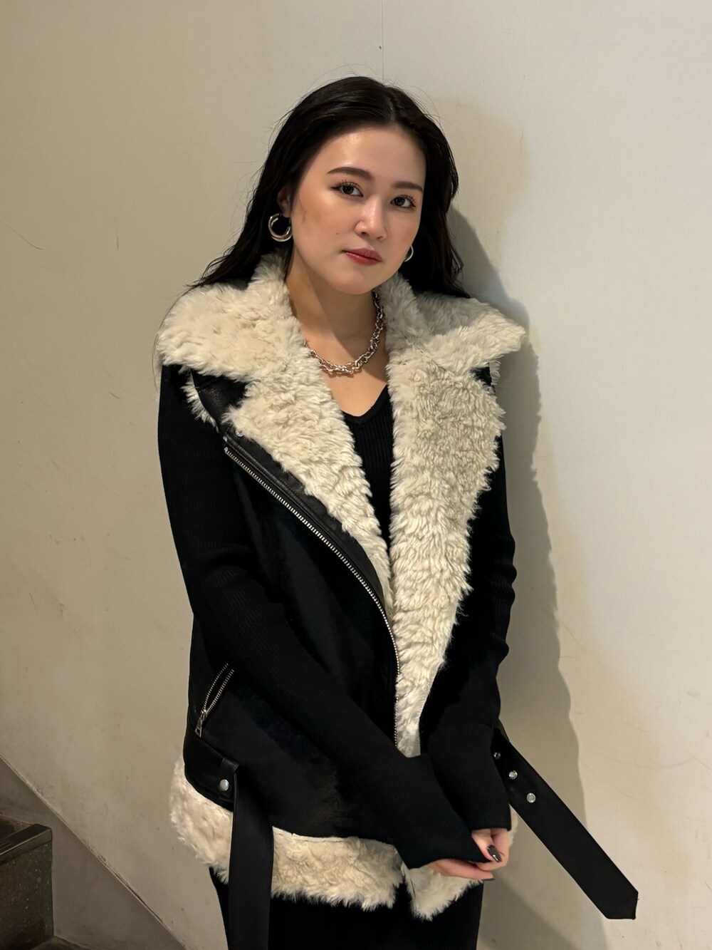 ブラック系のムートンコート、ブラック系のワンピース、ホワイト系のブーツを着用したレディースの秋コーディネートの4枚目の写真