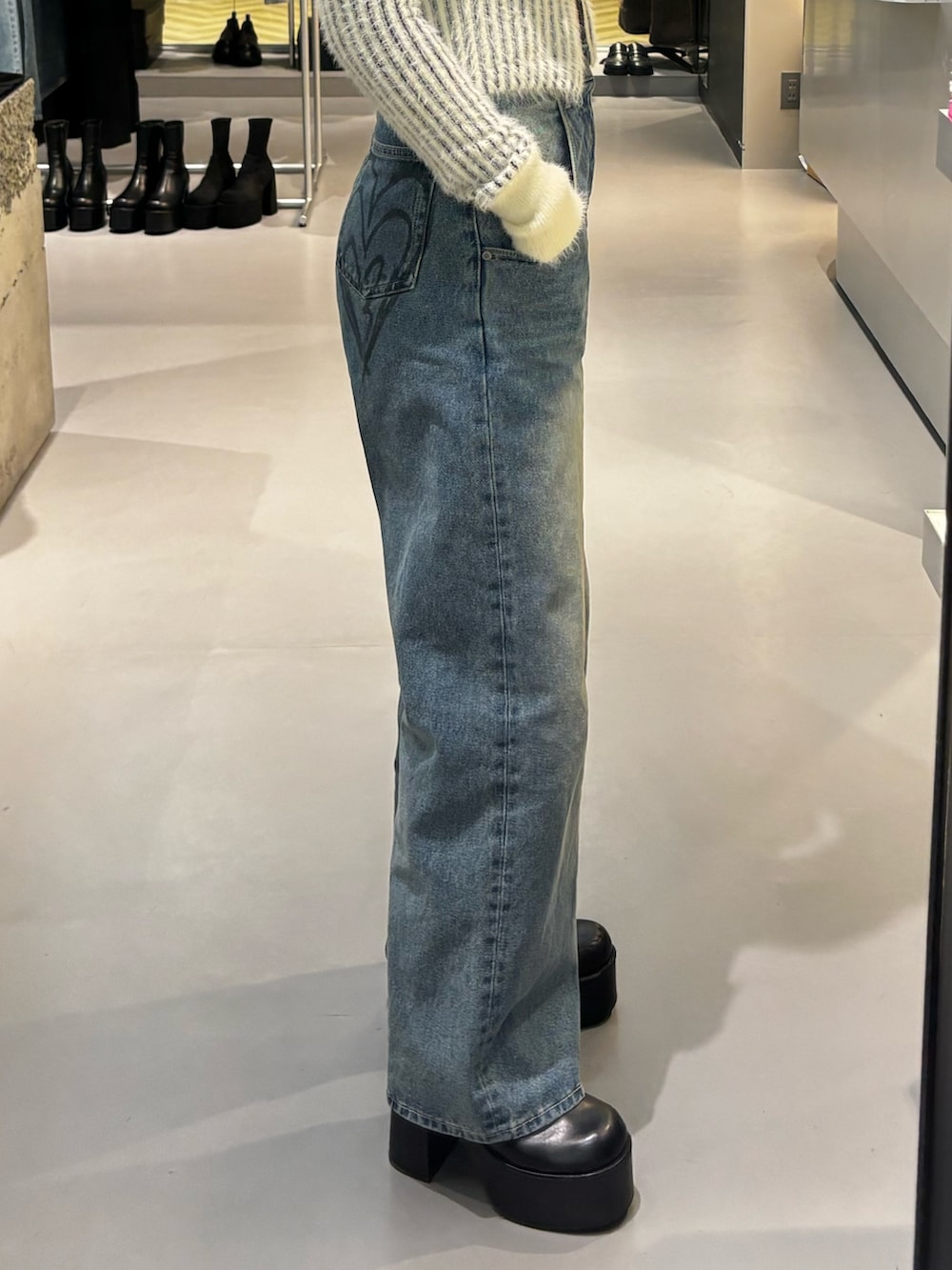 ブルー系のデニムパンツ、ブラック系のニット/セーター、ブラック系のブーツを着用したレディースの冬コーディネートの5枚目の写真