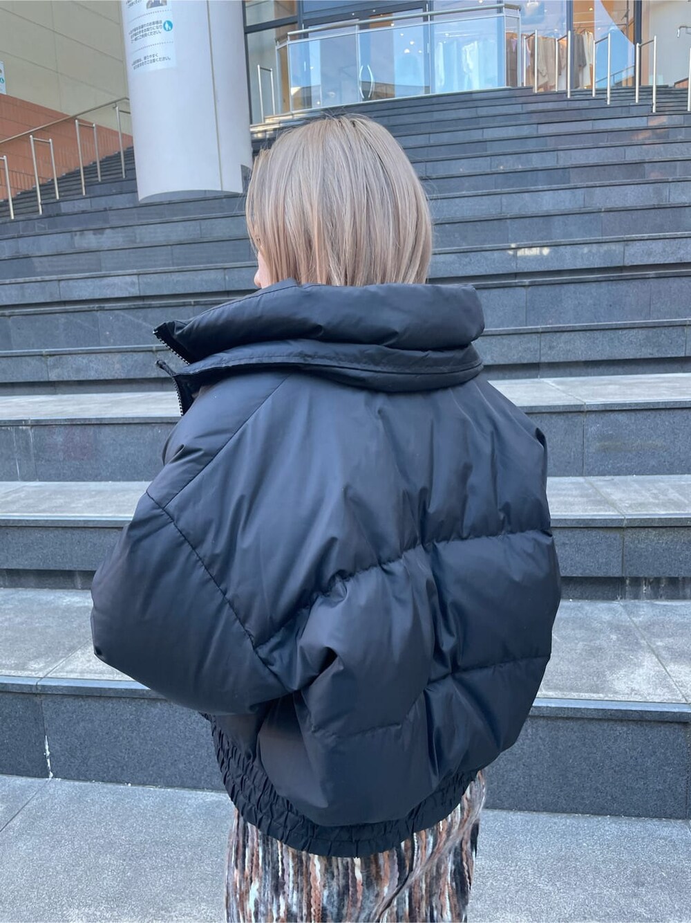 ブラック系のブーツ、ブラック系のダウンジャケット/コート、ブラウン系のスカートを着用したレディースの冬コーディネートの4枚目の写真