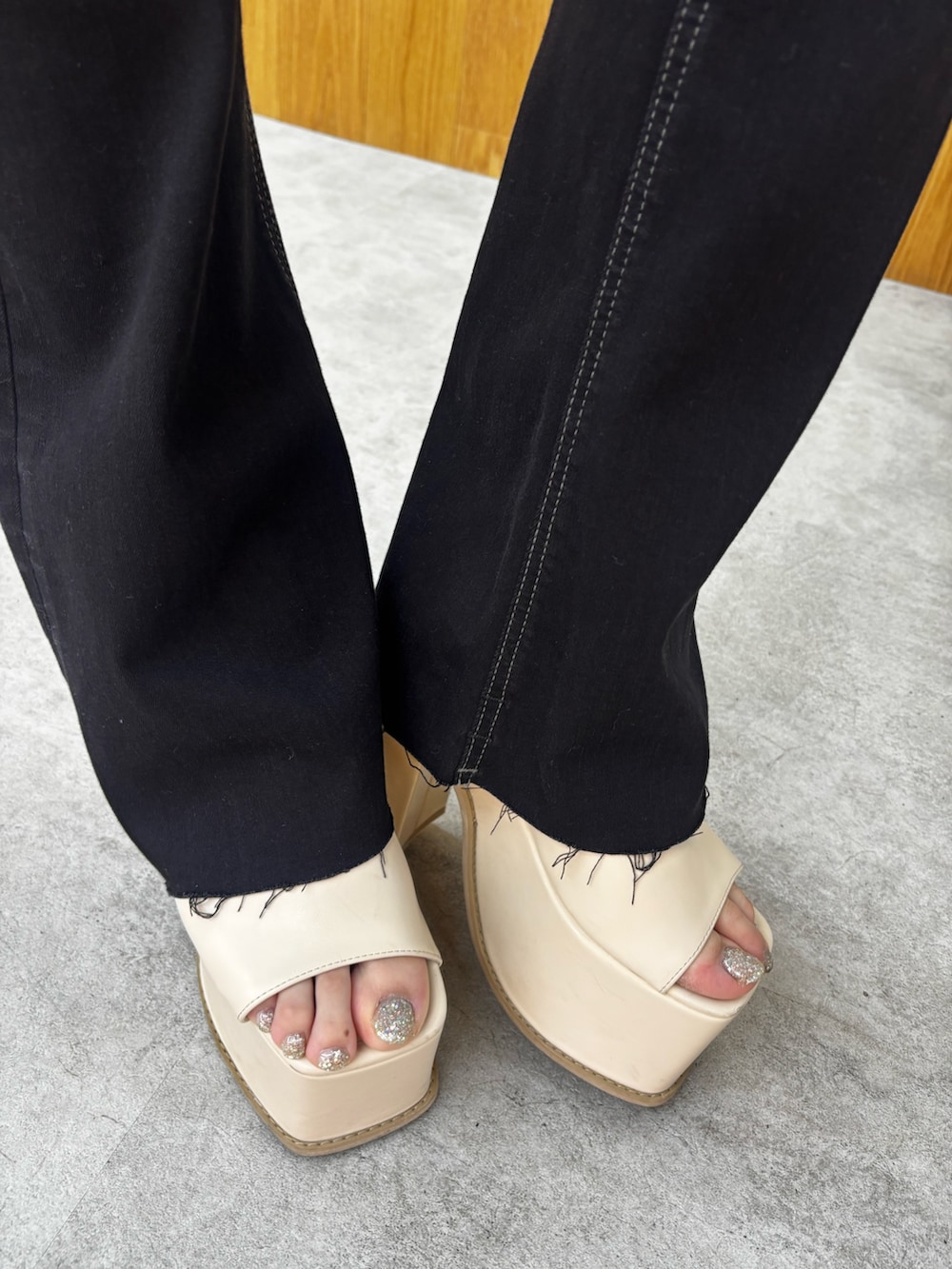ブラック系のデニムパンツ、ホワイト系のサンダル、ブラック系のニット/セーターを着用したレディースの春コーディネートの5枚目の写真