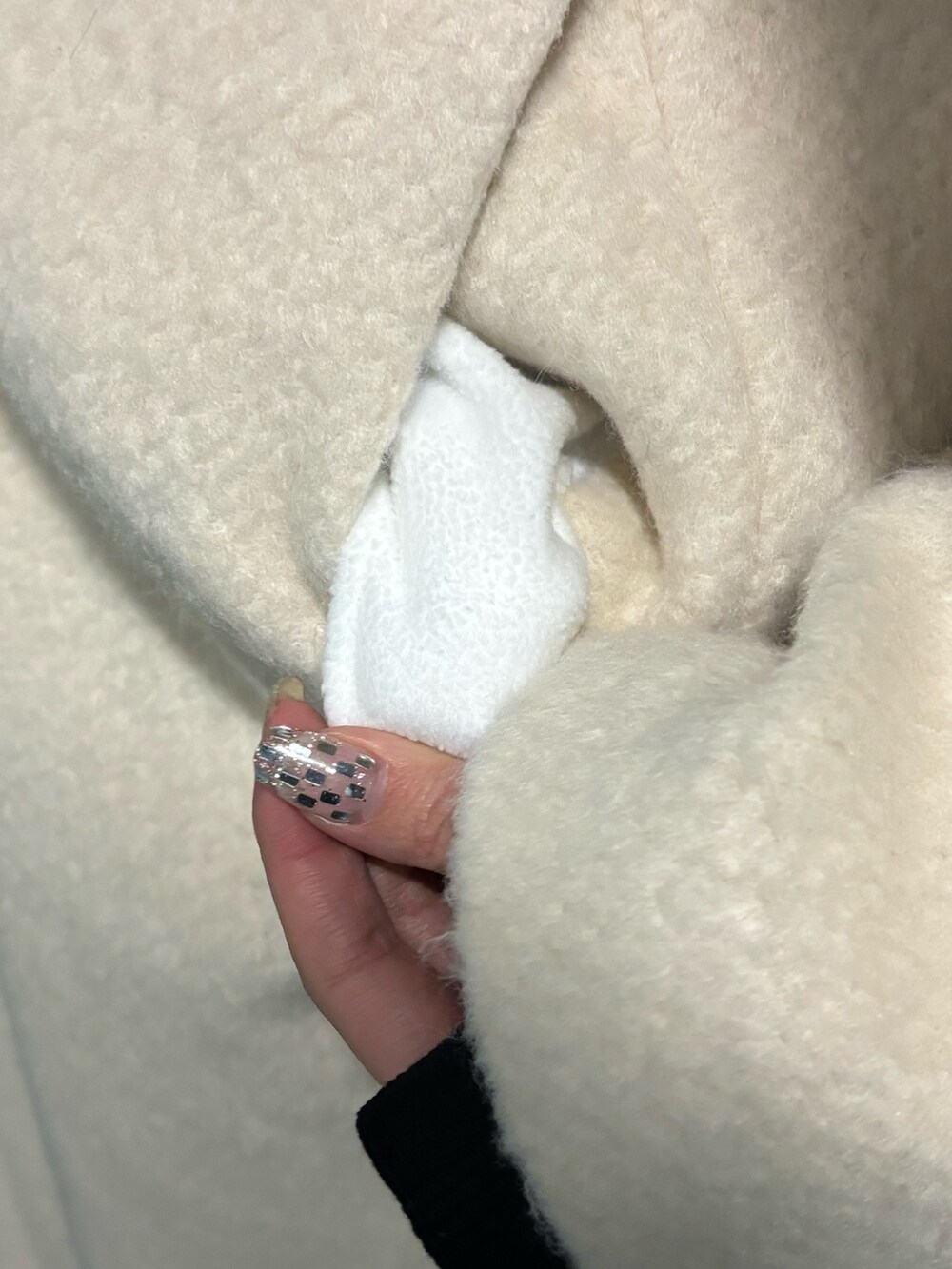 ホワイト系のチェスターコート、ブラック系のブーツ、ブラック系のハンドバッグを着用したレディースの冬コーディネートの7枚目の写真