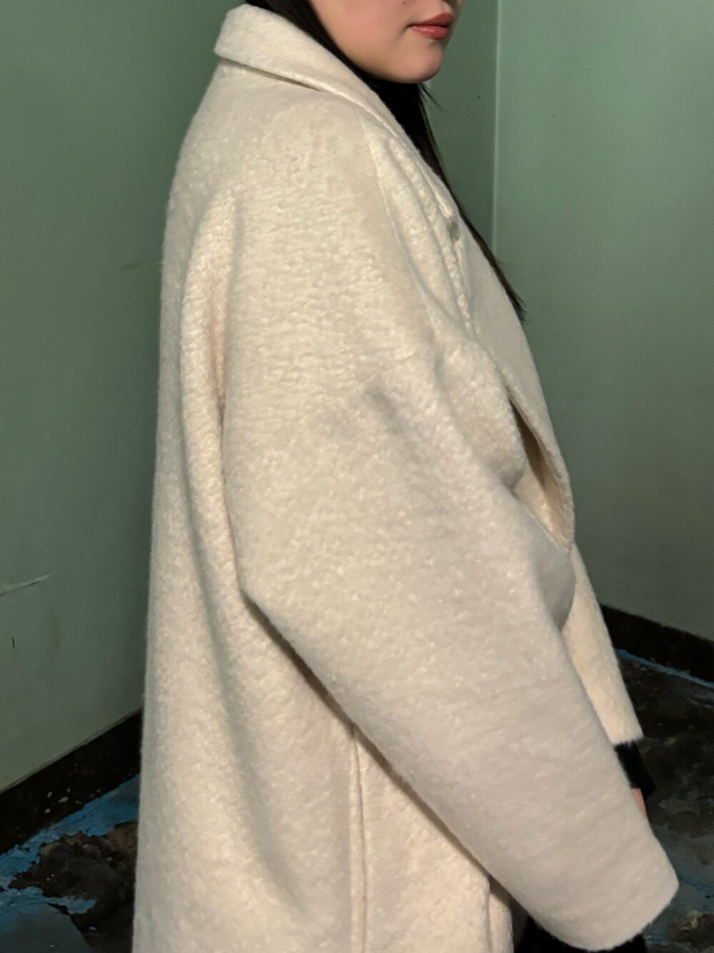 ホワイト系のチェスターコート、ブラック系のブーツ、ブラック系のハンドバッグを着用したレディースの冬コーディネートの5枚目の写真