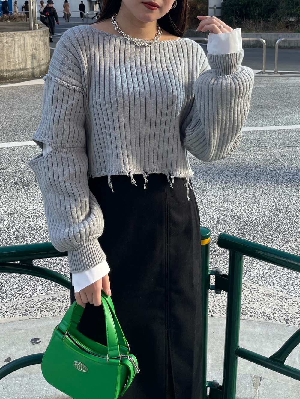 グレー系のニット/セーター、ブラック系のスカート、グリーン系のハンドバッグを着用したレディースの冬コーディネートの4枚目の写真