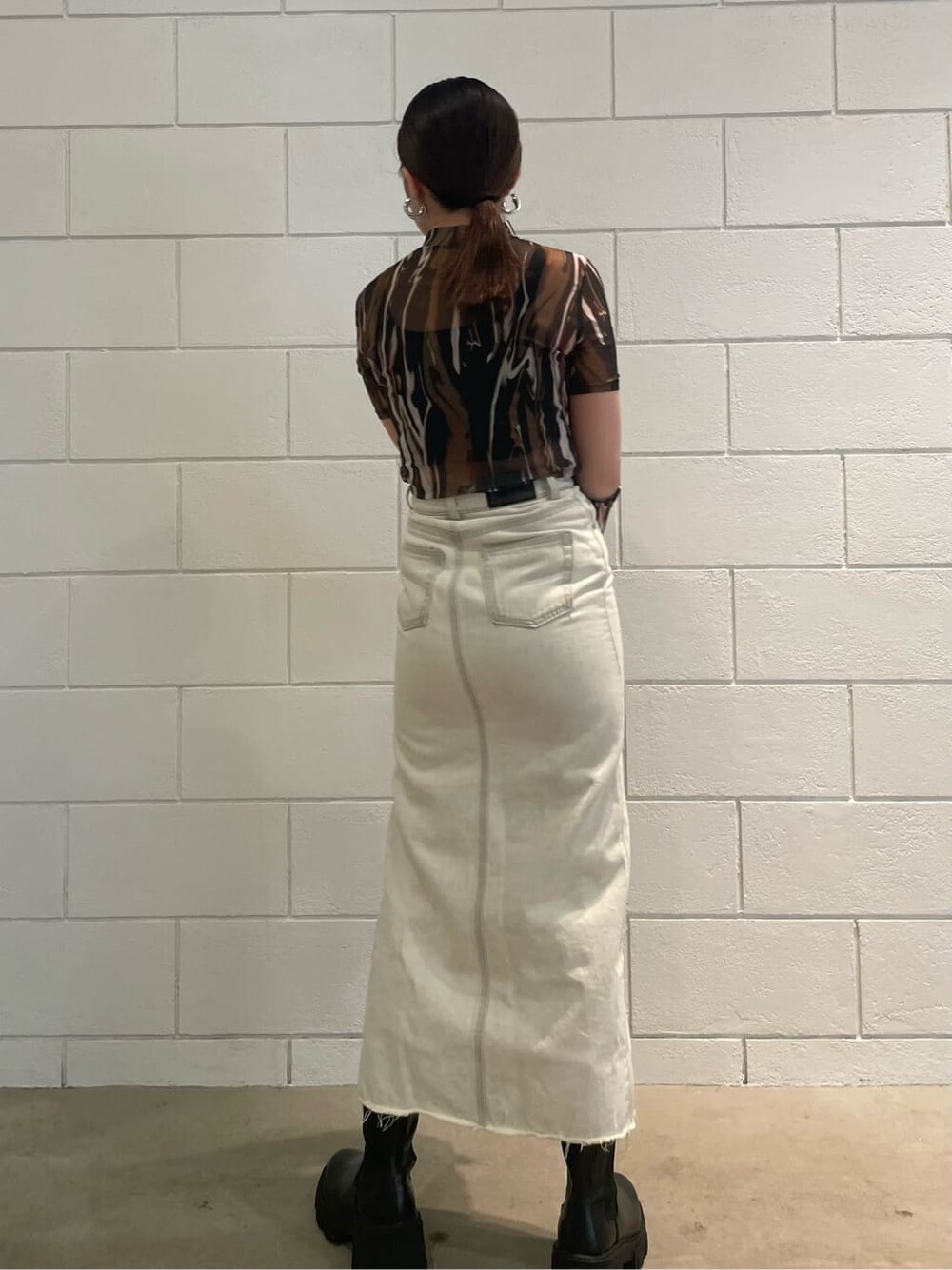 ホワイト系のスカート、ブラック系のブーツ、その他のTシャツ/カットソーを着用したレディースの夏コーディネートの3枚目の写真