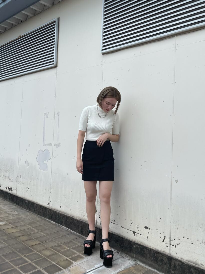 ブラック系のスカート、ブラック系のサンダル、ホワイト系のニット/セーターを着用したレディースの秋コーディネートの4枚目の写真
