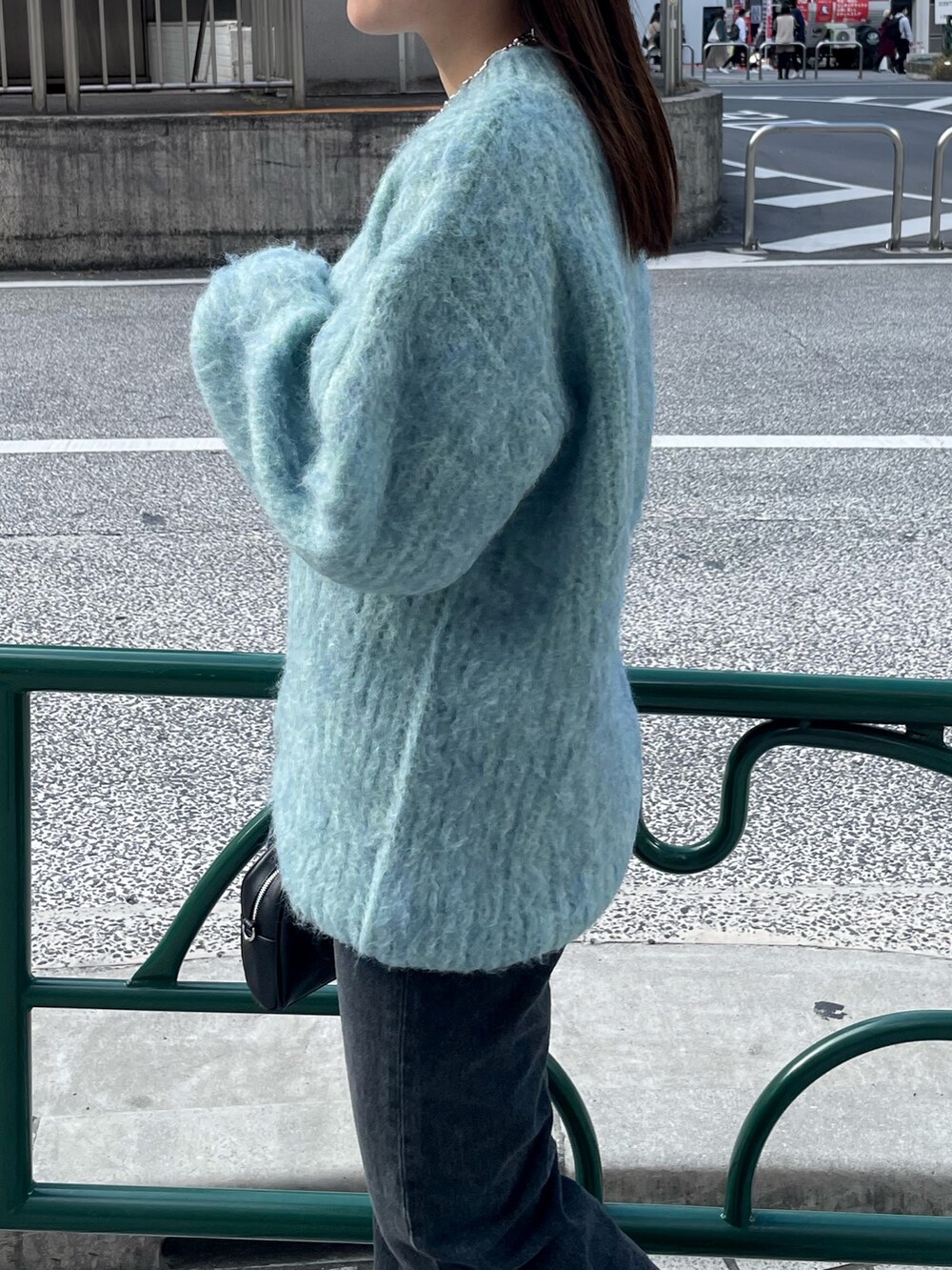 ブルー系のニット/セーター、ブラック系のデニムパンツ、ブラック系のブーツを着用したレディースの秋コーディネートの5枚目の写真