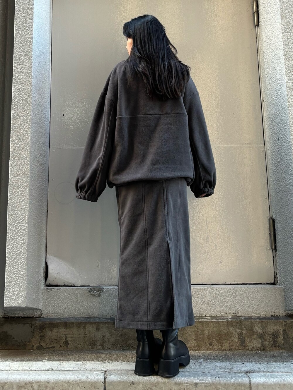 グレー系のTシャツ/カットソー、グレー系のスカート、ブラック系のブーツを着用したレディースの秋コーディネートの3枚目の写真