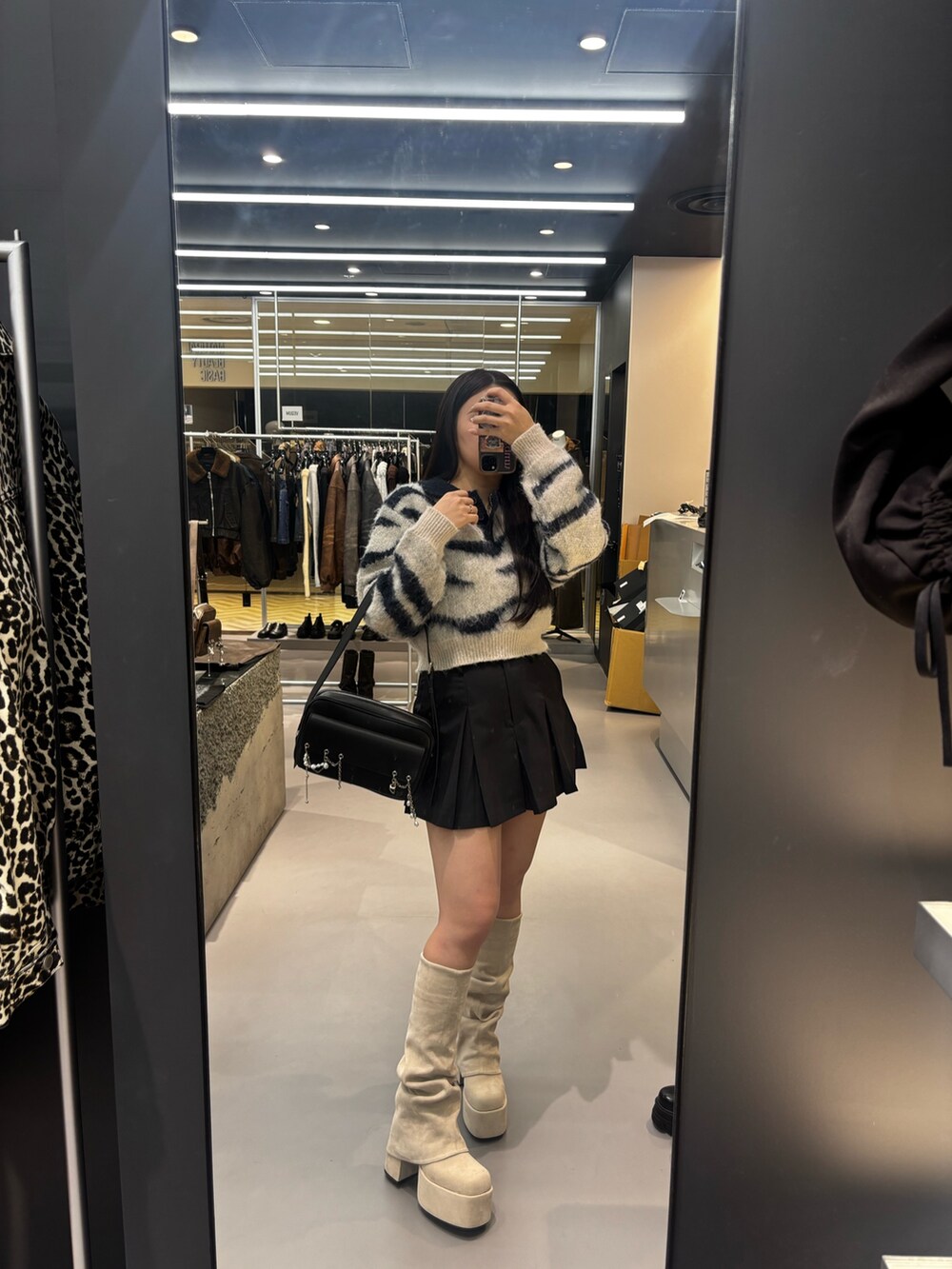 ホワイト系のブーツ、ブラック系のスカート、ブラック系のハンドバッグを着用したレディースの秋コーディネートの4枚目の写真