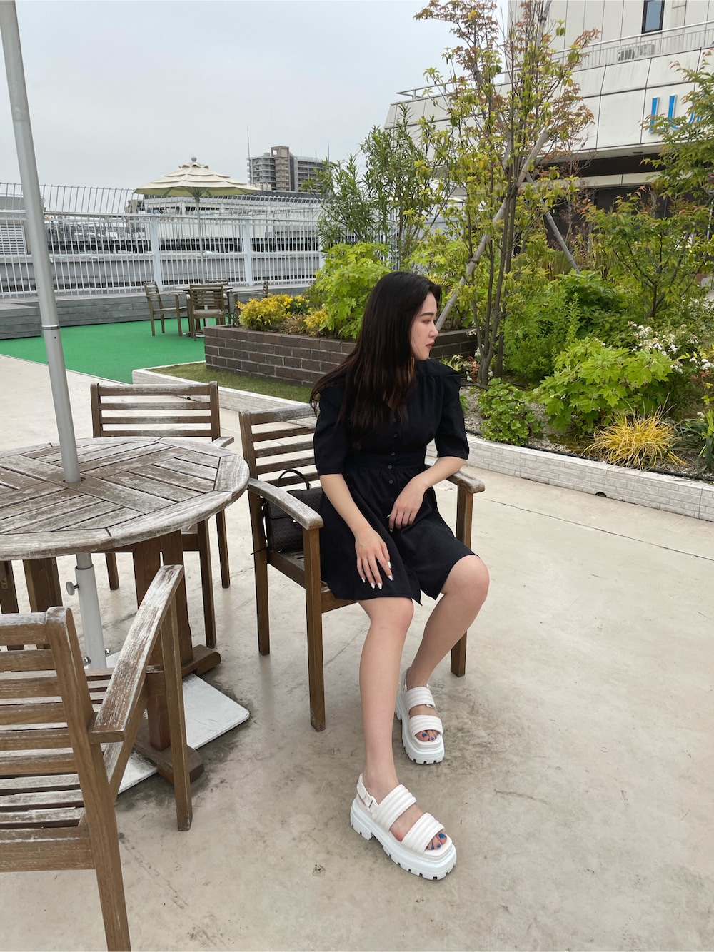 ブラック系のワンピース、ホワイト系のサンダル、ホワイト系のハットを着用したレディースの春コーディネートの6枚目の写真