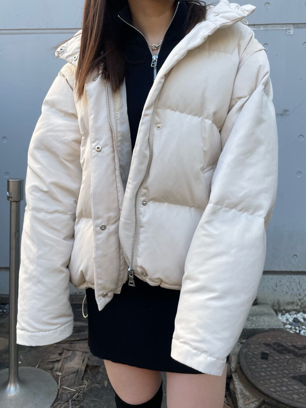 ホワイト系のダウンジャケット/コート、ブラック系のワンピース、ブラック系のブーツを着用したレディースの冬コーディネートの6枚目の写真