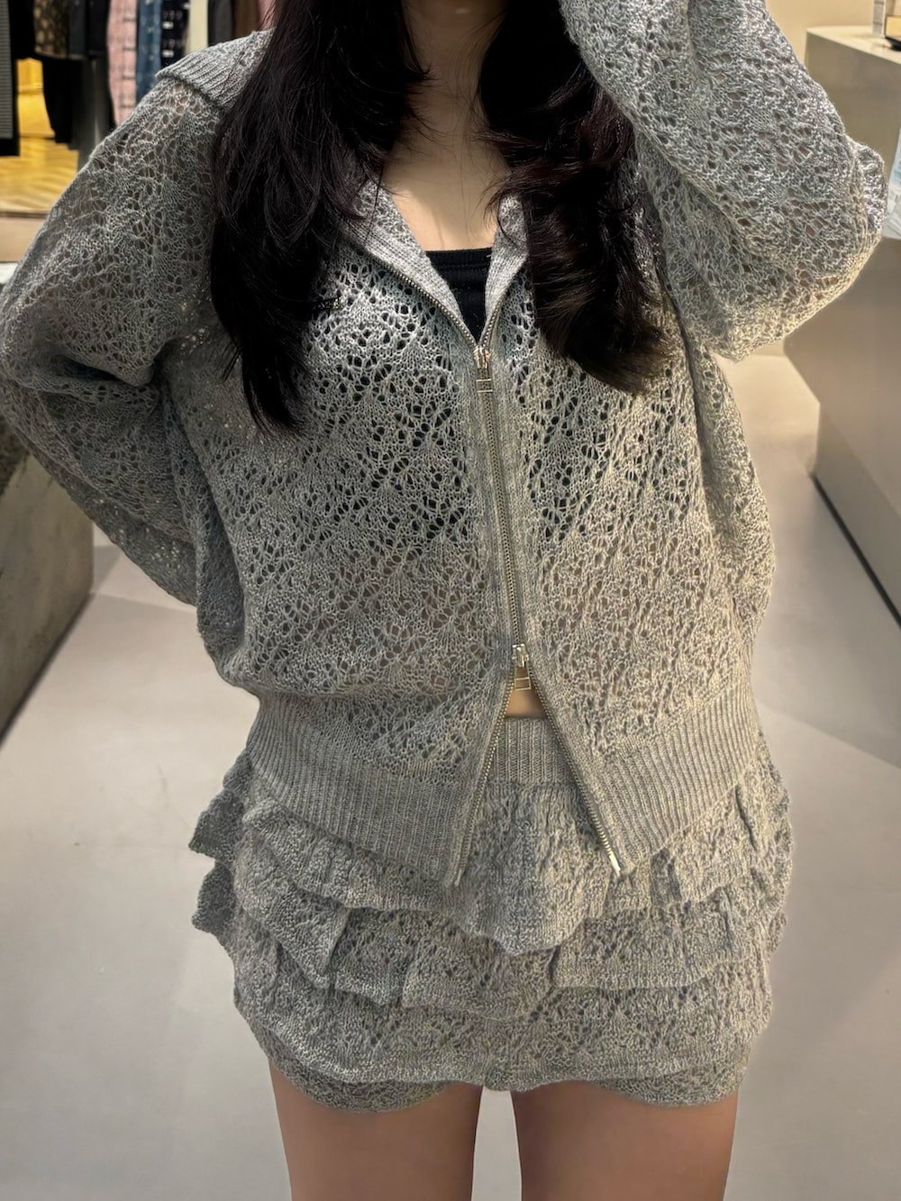 グレー系のパーカー、ブラック系のブーツ、グレー系のスカートを着用したレディースの冬コーディネートの3枚目の写真