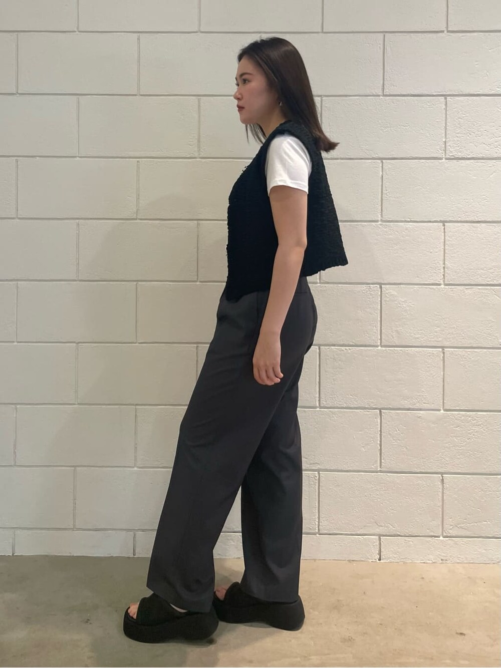 ブラック系のサンダル、ホワイト系のTシャツ/カットソー、ブラック系のベストを着用したレディースの夏コーディネートの2枚目の写真