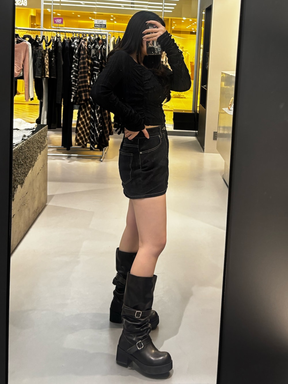 ブラック系のブーツ、ブルー系のスカート、ブラック系のTシャツ/カットソーを着用したレディースの冬コーディネートの2枚目の写真