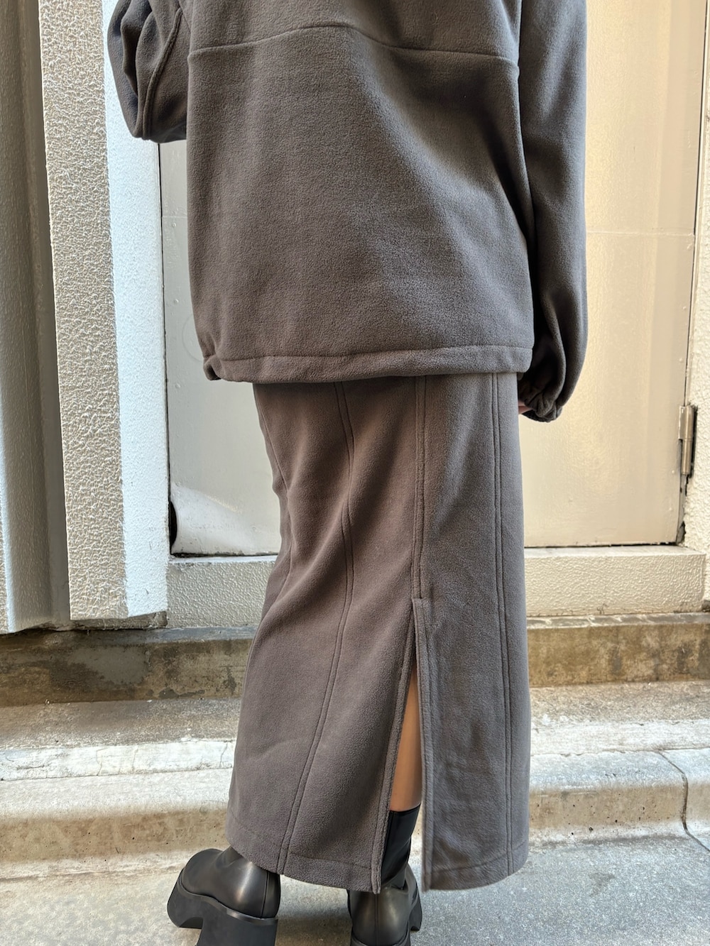 グレー系のTシャツ/カットソー、グレー系のスカート、ブラック系のブーツを着用したレディースの秋コーディネートの8枚目の写真